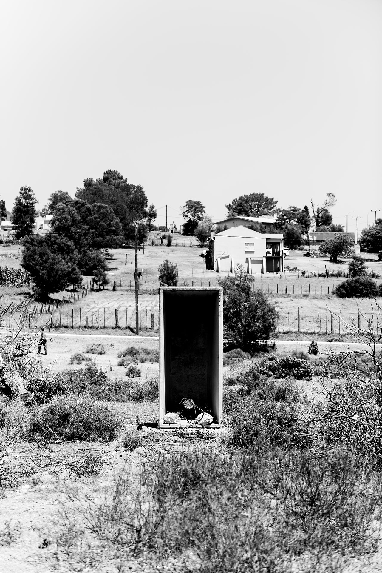 An old outside toilet structure shot in stark black and white minimilism.