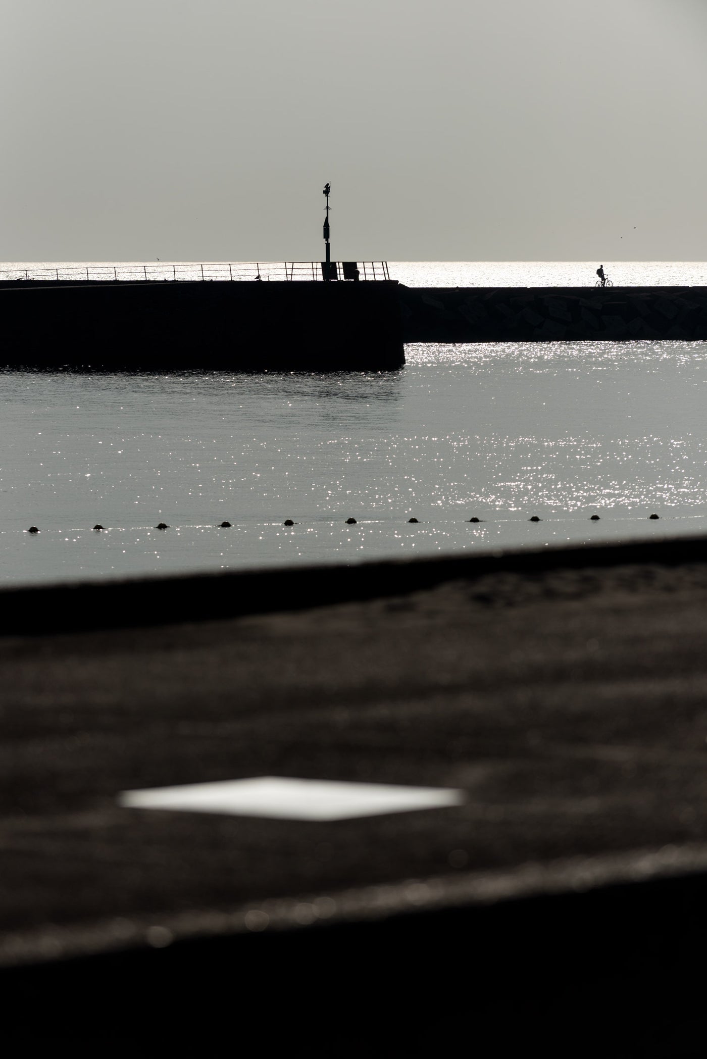 A view of the Scheveningen Harbour, with a cyclist on the sea wall in the distance.