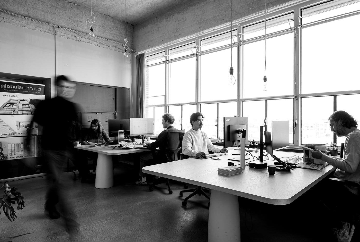 Black and white office scene with people working at desks.