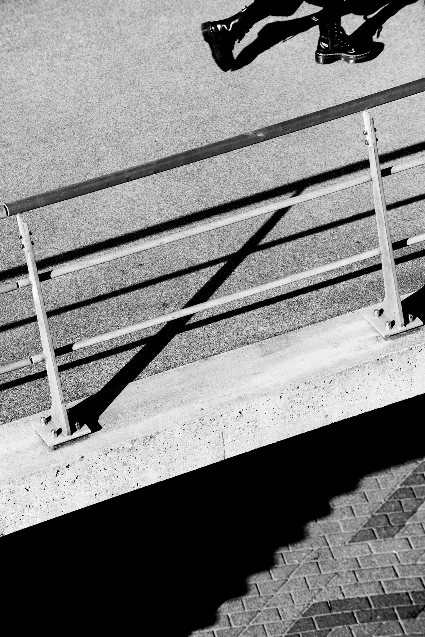 A woman walks on a concrete sidewalk in Rotterdam. Only her feet are visible.
