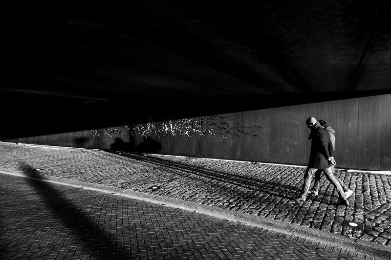 A couple walk under a bridge in Rotterdam.
