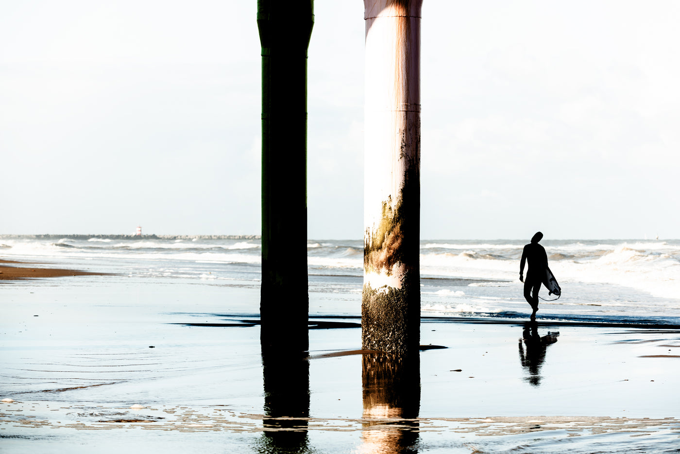 A surfer walks, stretches, under the pier at Scheveningen.
