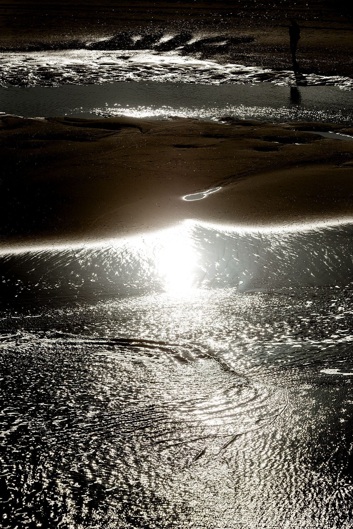 The sunlight bouncing of the shallow water, on the beach at Scheveningen