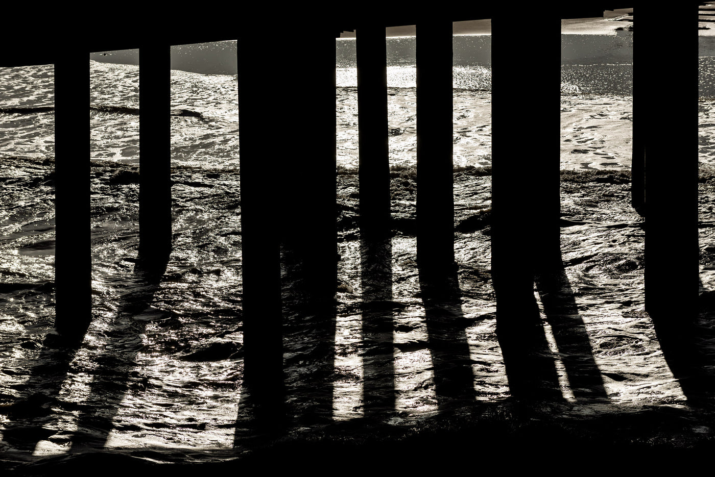 The sun dramatically lights the ocean water beneath The Pier in Scheveningen.