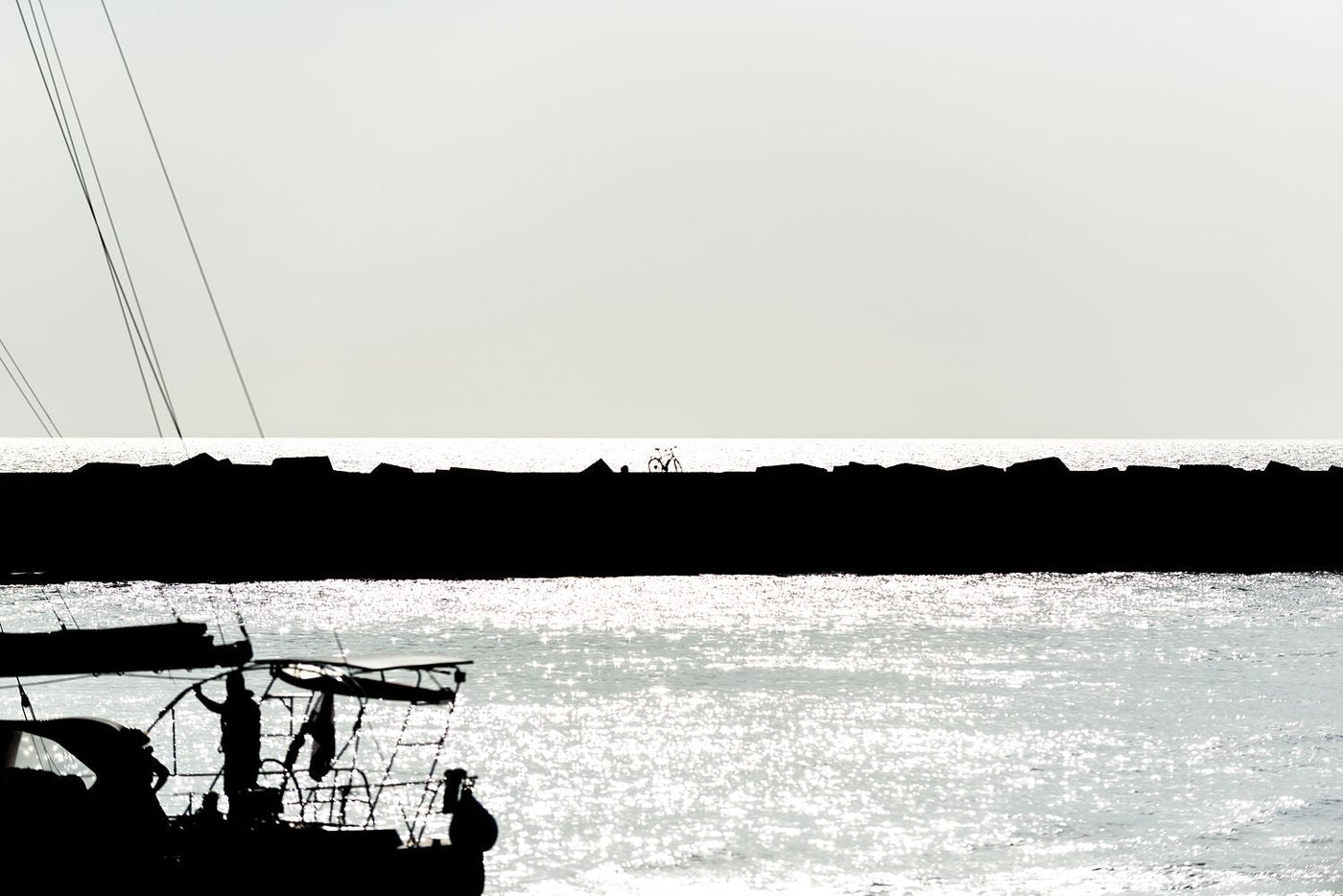 A yacht silhouetted with a bicycle in the background passes through the harbour area at Scheveningen