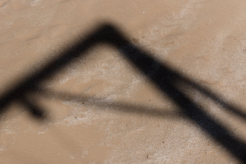 A shadow cast on the beach by a crane.