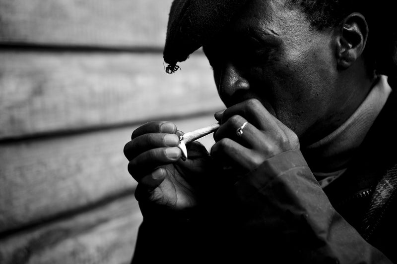 A man lights a cigarette in a township, South Africa.