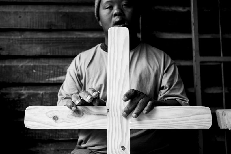 A man finishes making a burial cross at Die Werkswinkel.