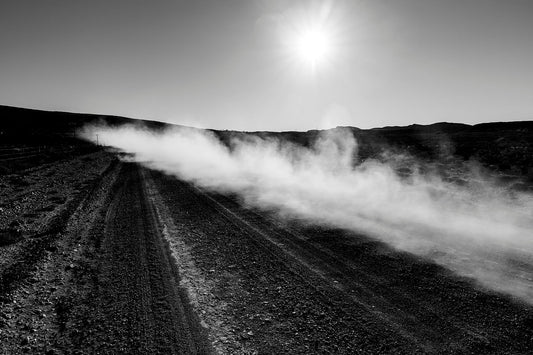 Dust rises after a car passes on a dirt road in the Little Karoo in this black and white fine art photograph