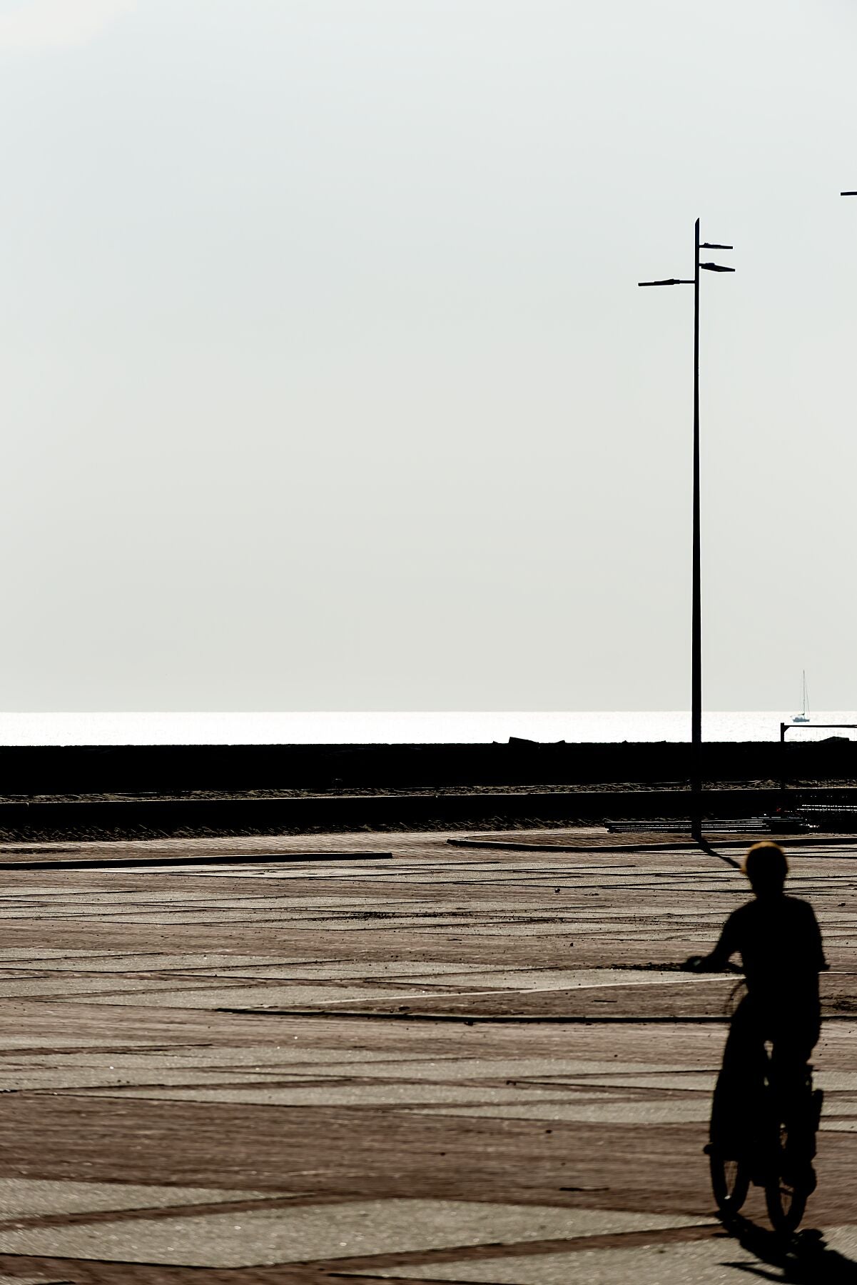 A cyclist captured in the concrete landscape leading to the Northern Harbour Pier at Scheveningen.
