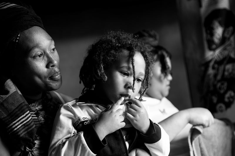 A family in dramatic lighting in a township home, South Africa.