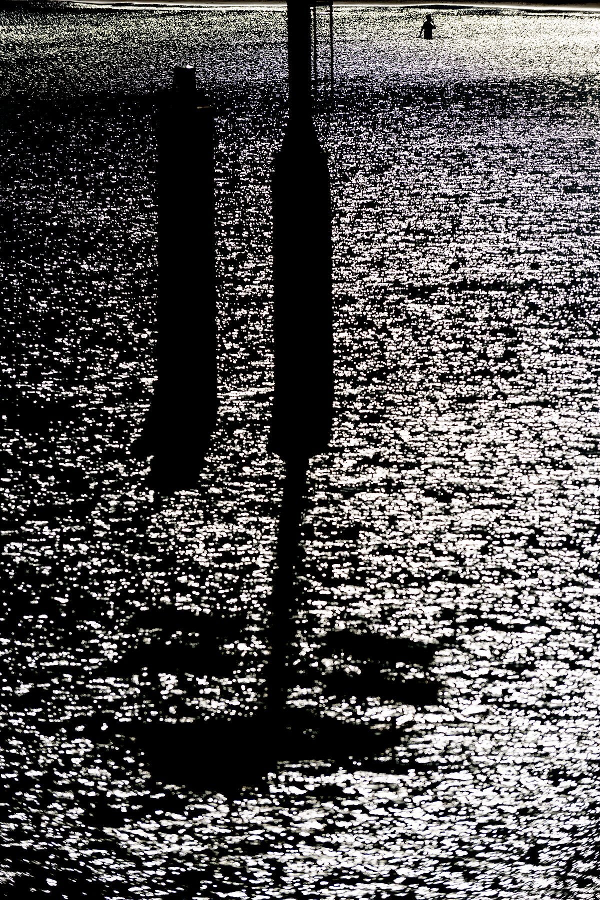 A swimmer in the sea and sun. Shot from the Northern Pier at Scheveningen Harbour.