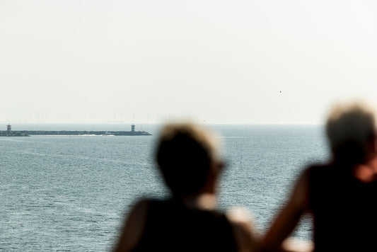 Two figures in soft focus atop The Pier at Scheveningen with the harbour walls in the distant background.