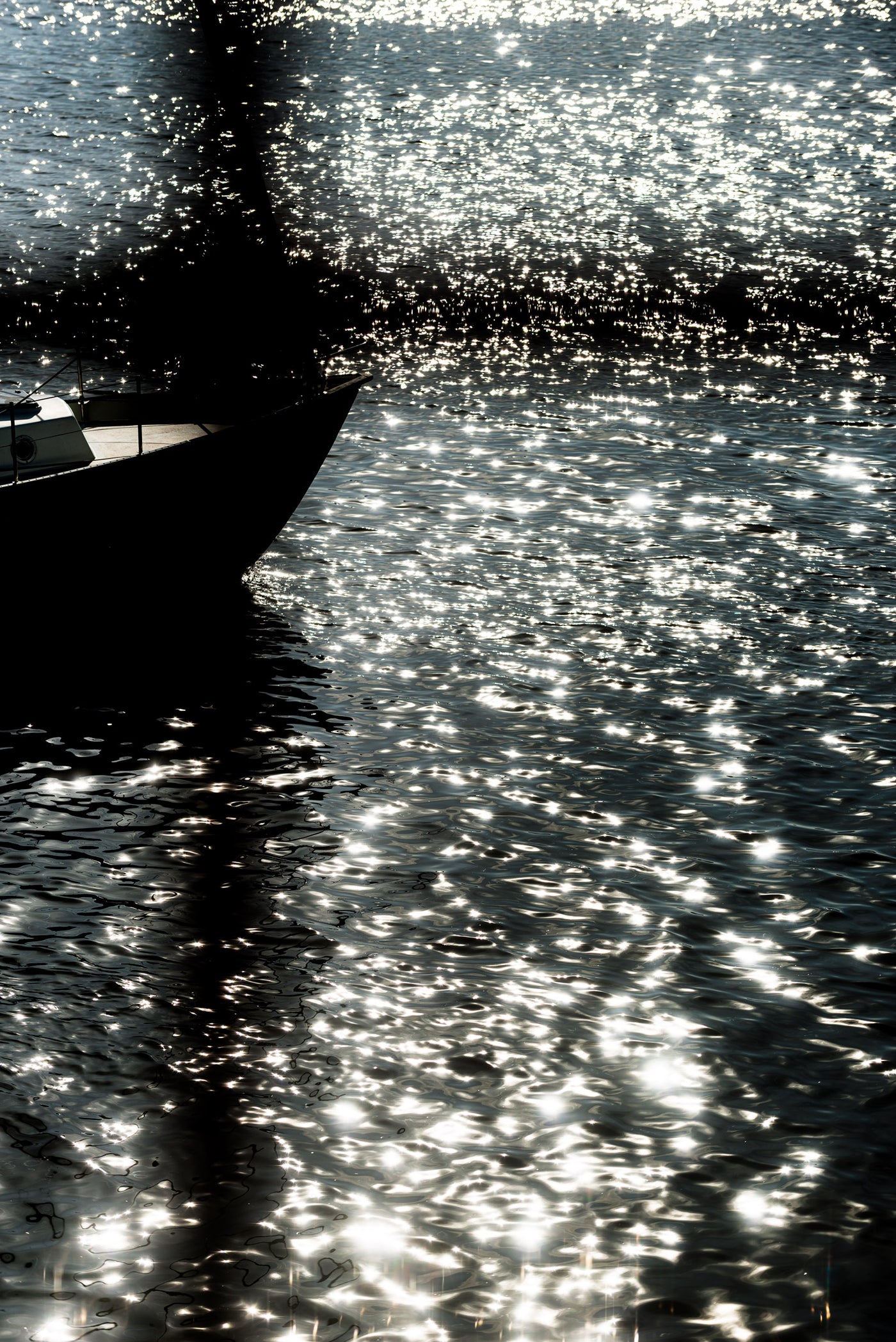 Light reflects on the water of scheveningen harbour as a yacht passes through.