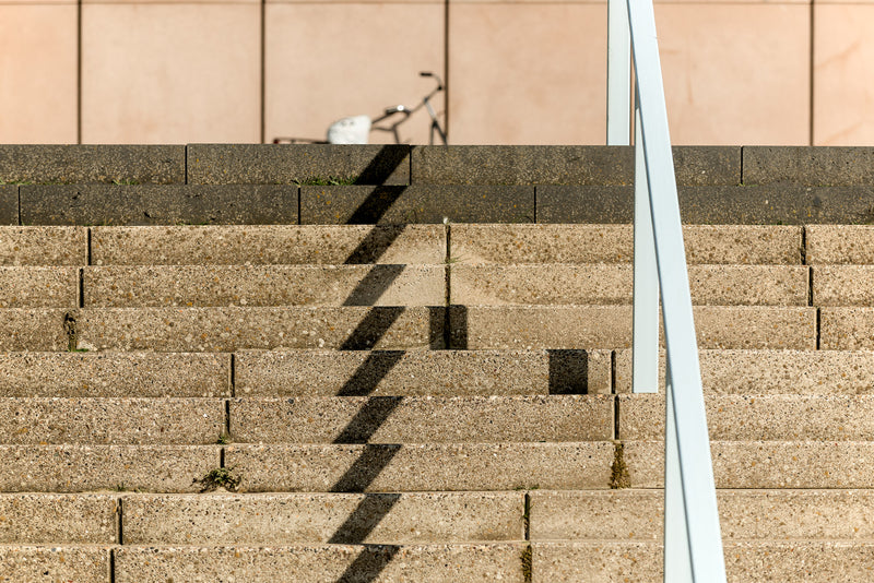 A flight of stairs, concrete and a bicycle on a promenade.